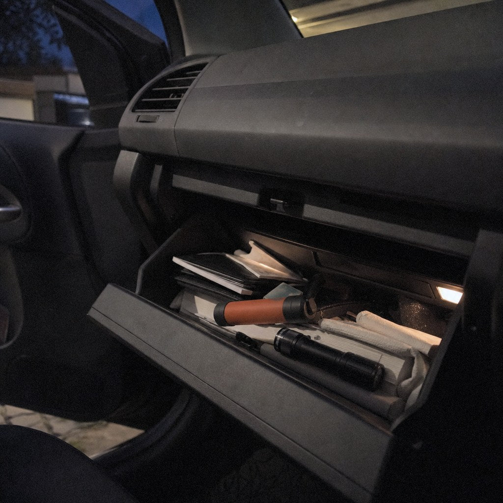 A survival straw in an open car glovebox next to a flashlight